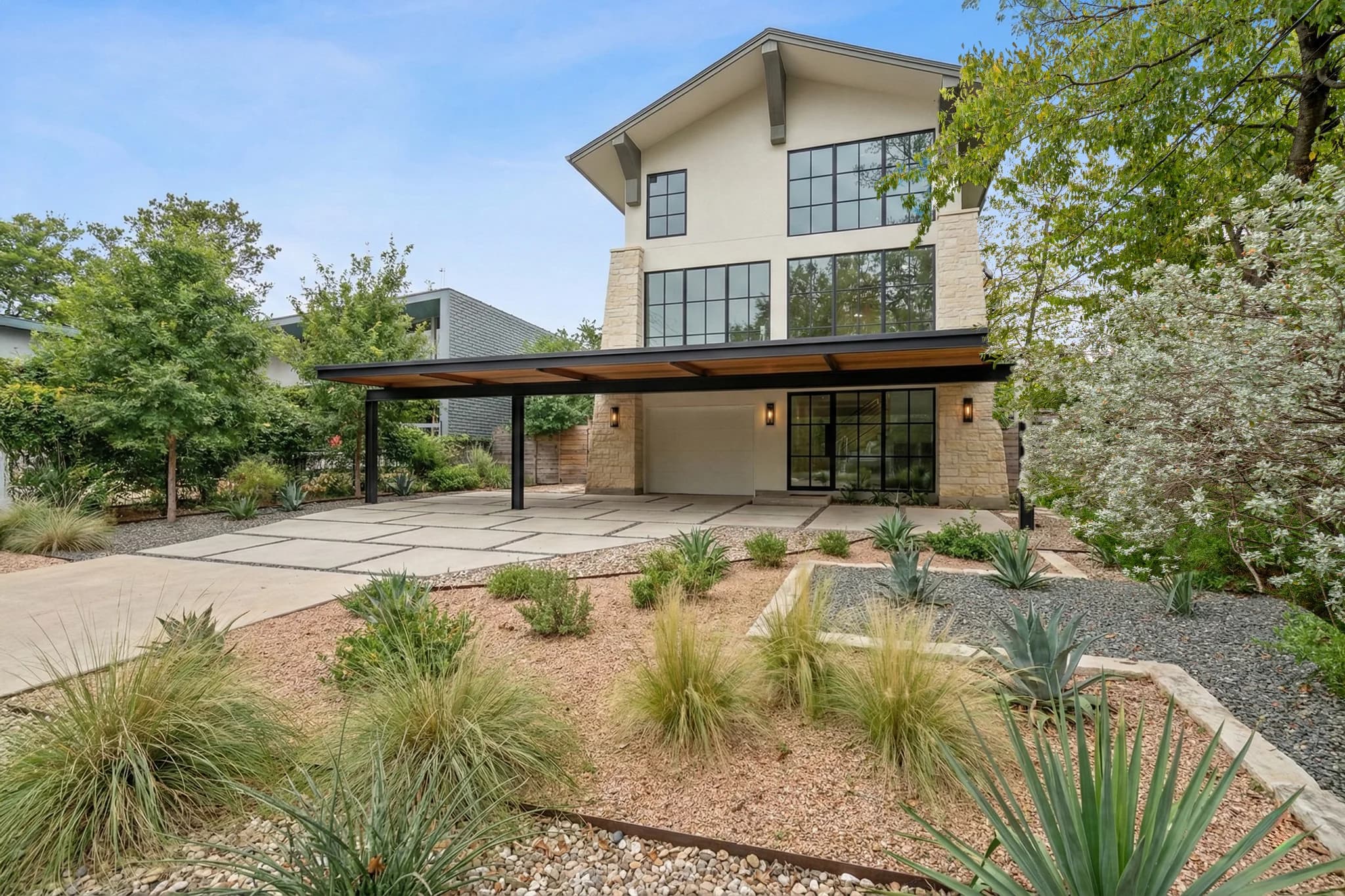 Before day-to-dusk editing: Modern two-storey house with desert landscaping and a covered outdoor area