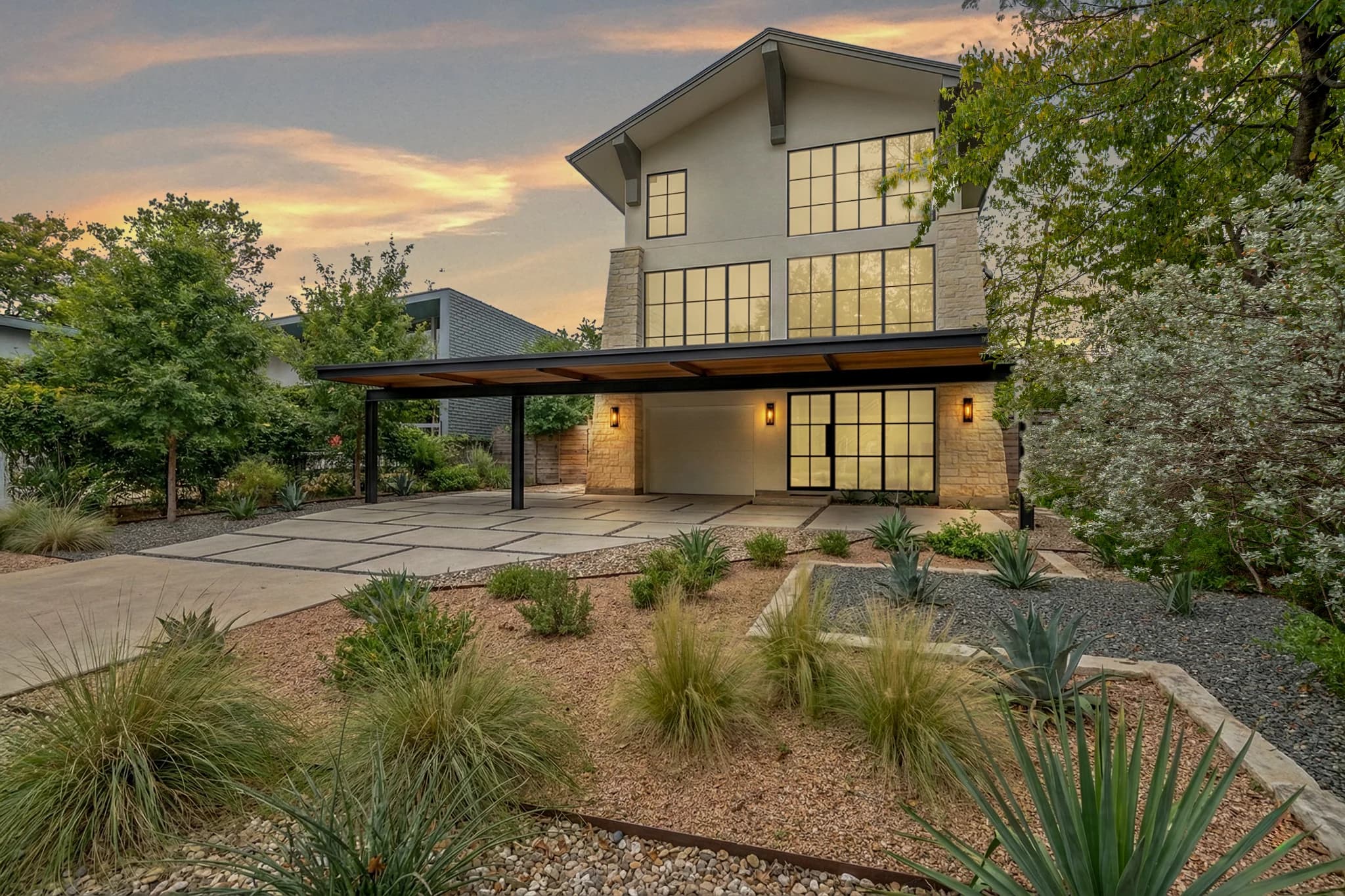 After day-to-dusk editing: Modern two-storey house with desert landscaping and a covered outdoor area